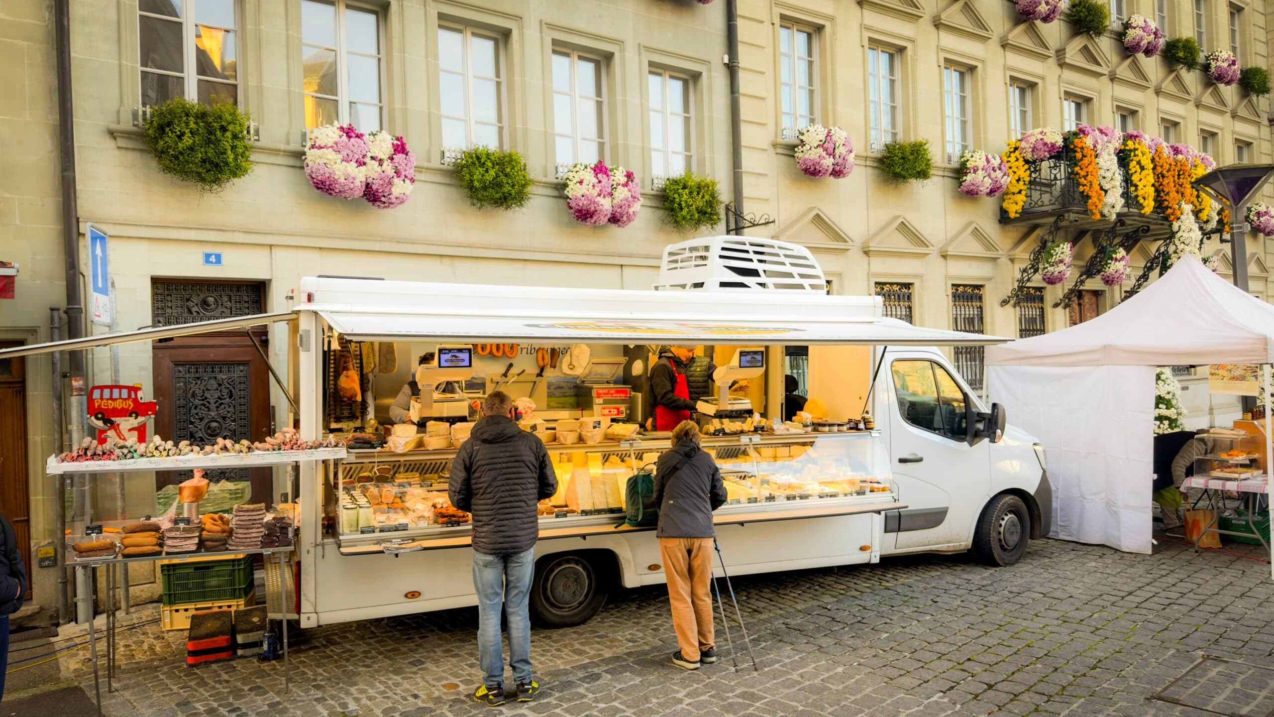 Étal de fromages et charcuteries du Chalet Fribourgeois sur un marché fribourgeois